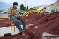 Fisherman repairing fishing net in place Kali, island Ugljan, Dalmatia, Croatia